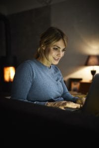 Romanian language subjunctive mood read by a smiling woman using laptop at home in the evening