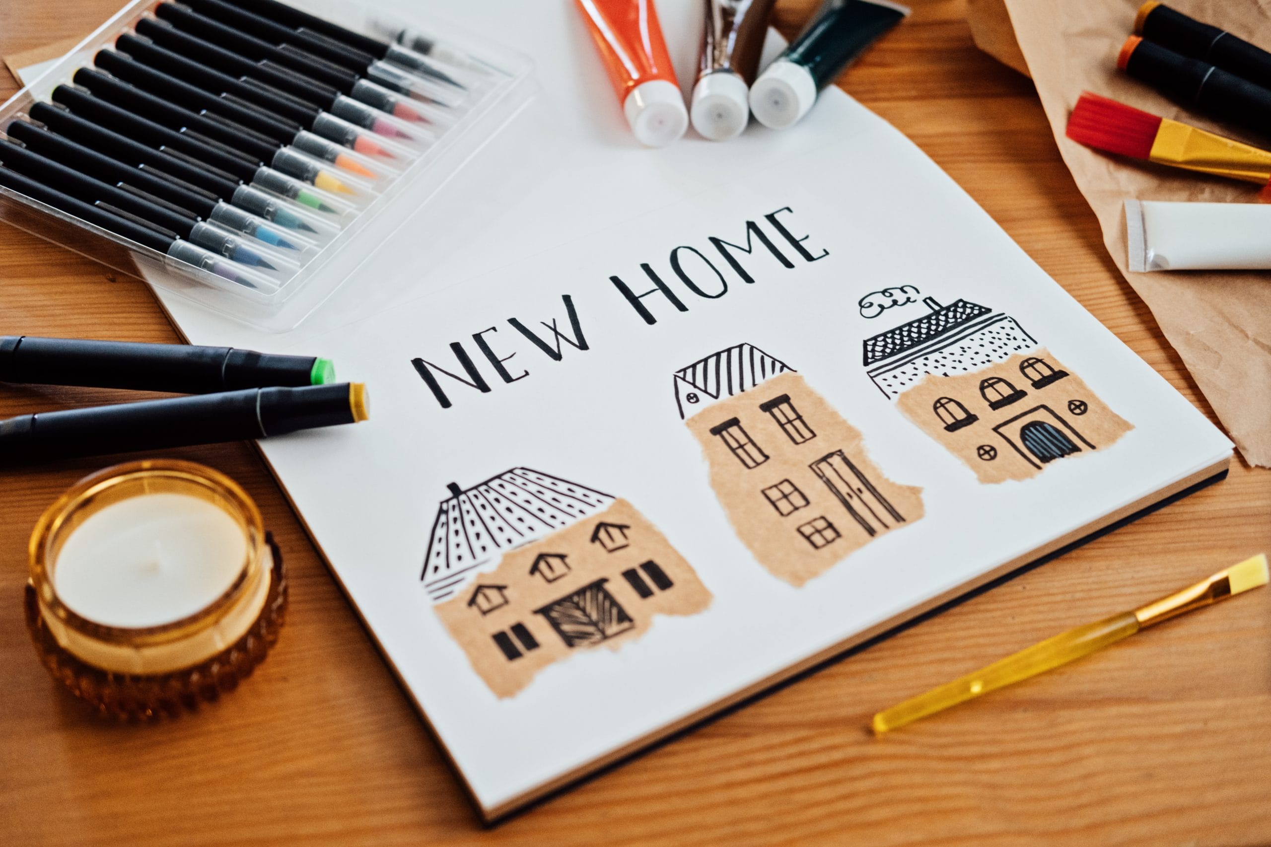 Learn Romanian to describe your home. Drawing of several houses text new home on table with paints, brushes and stationery, supplies for drawing and craft. Dreaming about new house.