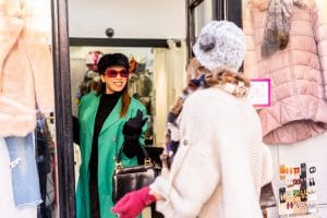 shopping in the city and being attended by a shop assistant, a Young blonde girl is enjoying to learn Romanian shopping expressions