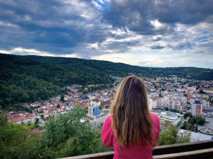Express future in Romanian by a young woman who is looking at the city from the hill
