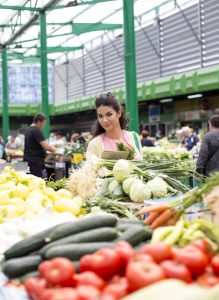 Pretty young woman learned Romanian A2 food vocabulary and now she is buying vegetables on the market after she